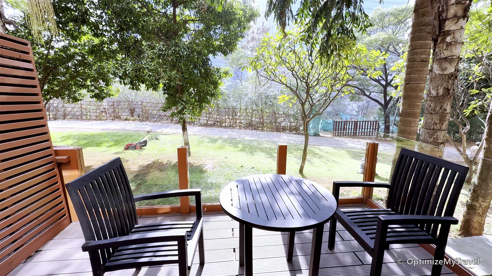 Two chairs and a round table on the balcony overlooking the hotel's trees and lawn